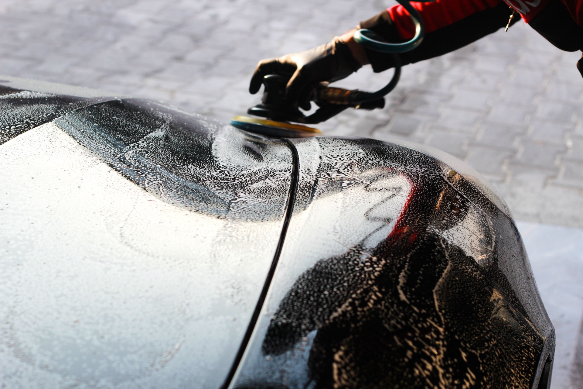 Detailing brush passing over a wet hood during an exterior wash.